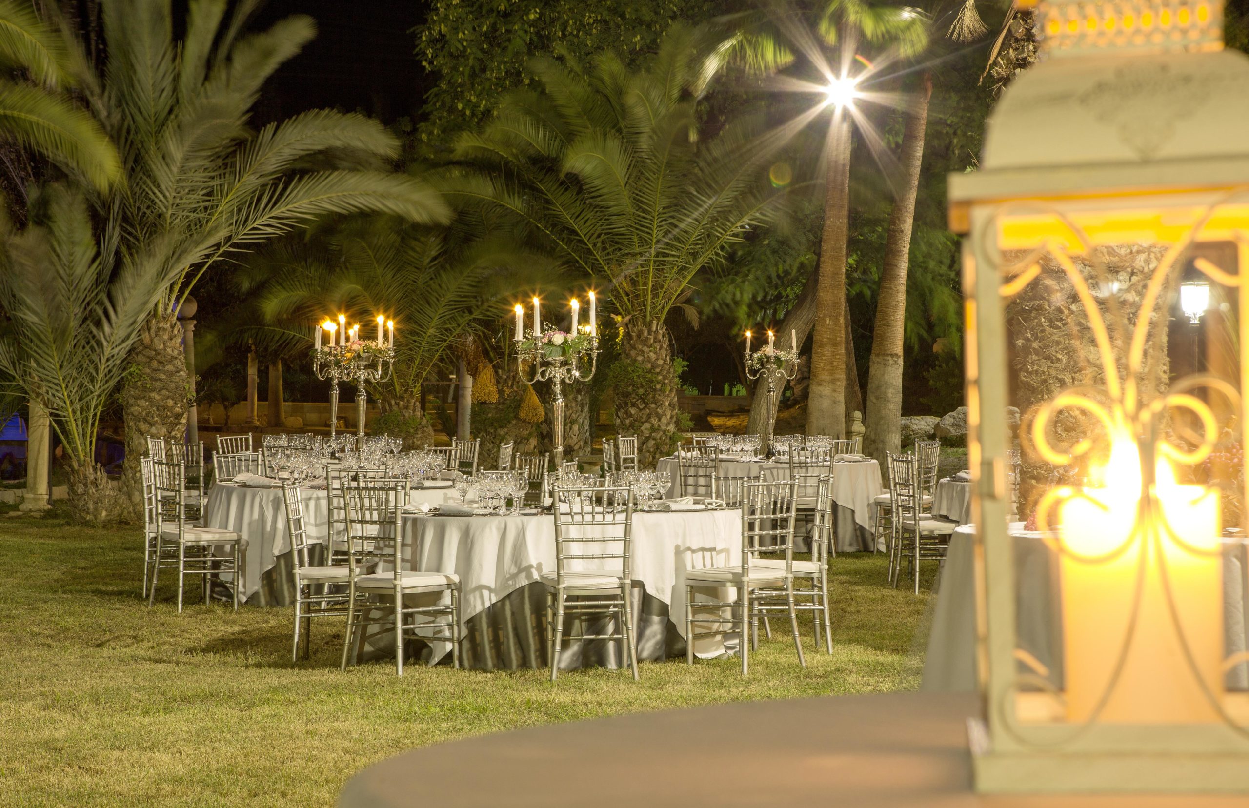 Vista tras foco de velas de salón exterior iluminado por candelabros.